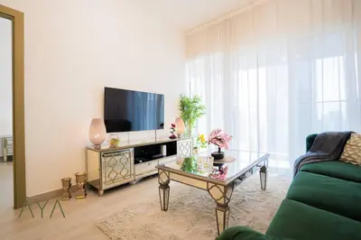 a living room with a tv and a coffee table at Elegant 1BR Retreat with Rooftop Pool in JVC By ĀYA Boutique in Dubai
