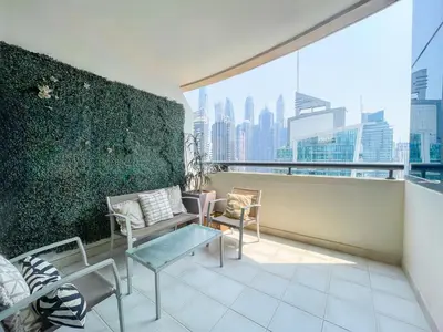 an apartment balcony with a green wall and chairs at RH - Marina View Getaway, Spacious One-Bedroom with Terrace in Dubai Marina in Dubai