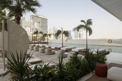a rooftop patio with lounge chairs and palm trees at Modern Studio at Upside Living, Business Bay with Burj Khalifa View in Dubai