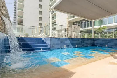 a swimming pool with a fountain in front of a building at GuestReady - Stylish living at Reva Residence in Dubai