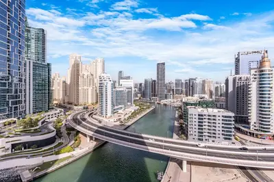 a city with a bridge over a river and buildings at Luxurious 2BR Home with Stunning Marina Skyline View in Dubai