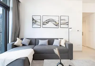 a living room with a gray couch and pictures on the wall at Downtown Luxe, steps to Burj Khalifa 4BDR in Dubai