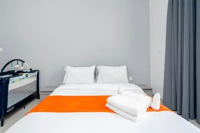 a bedroom with two beds with an orange and white blanket at Cozy Studio - Dubai Land -Tiger V Tower in Dubai
