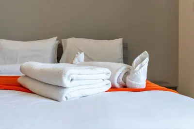 a pile of towels sitting on top of a bed at Cozy Studio - Dubai Land -Tiger V Tower in Dubai
