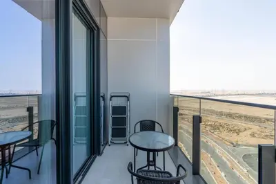 a balcony with two tables and a view of the desert at Cozy Studio - Dubai Land -Tiger V Tower in Dubai
