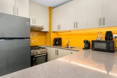 a kitchen with white cabinets and a counter top at Cozy Studio - Dubai Land -Tiger V Tower in Dubai