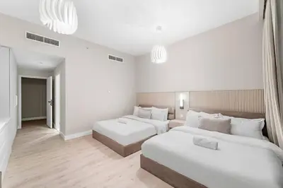 two beds in a room with white walls and wood floors at Stunning Sea & Palm View 2BR, Steps from JBR Beach & Waterfront in Dubai