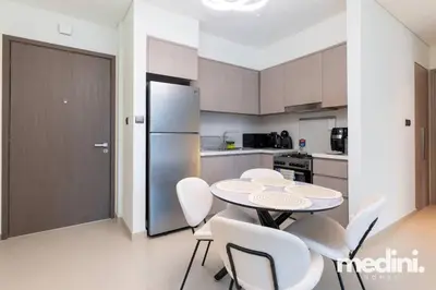 a kitchen with a table and chairs and a refrigerator at Prime location - ACT 1 ACT 2 - Downtown in Dubai