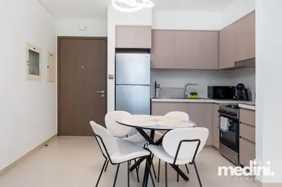 a kitchen with a table and white chairs in a kitchen at Prime location - ACT 1 ACT 2 - Downtown in Dubai