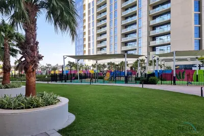 a park with palm trees and a large building at Special Offer Refined Studio with City Views by Deluxe Holiday Homes in Dubai
