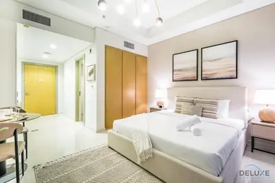a bedroom with a large white bed and a desk at Special Offer Refined Studio with City Views by Deluxe Holiday Homes in Dubai