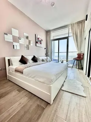 a bedroom with a large white bed with a large window at Lujo Dubai Marina in Dubai