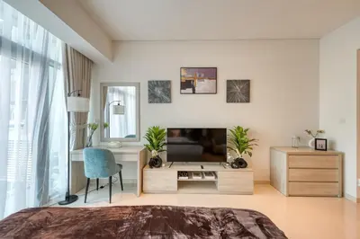 a bedroom with a bed and a desk and a television at Beachfront Studio Right by Nakheel Mall in Dubai