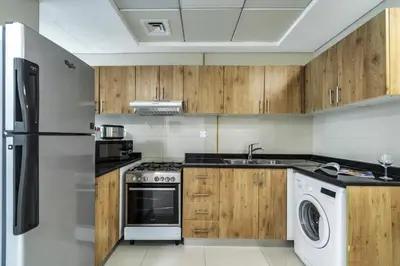 a kitchen with wooden cabinets and a washer and dryer at ShoresInn - Marvelous Marina View In Dubai in Dubai