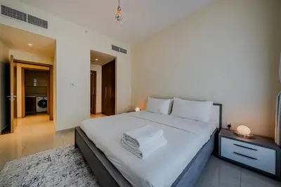 a bedroom with a large bed with white sheets at Modern 2BDR Apartment I Dubai Hills I City View I Mulberry at Park Heights in Dubai