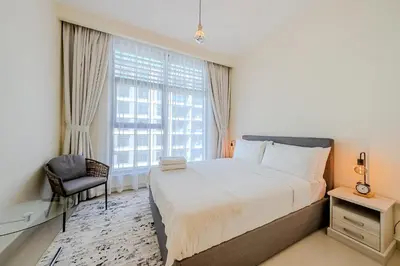 a bedroom with a bed and a chair and a window at Modern 2BDR Apartment I Dubai Hills I City View I Mulberry at Park Heights in Dubai