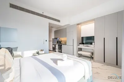 a bedroom with a white bed and a kitchen at Appealing Studio in MAG EYE 890, Mohammad Bin Rashid City by Deluxe Holiday Homes in Dubai