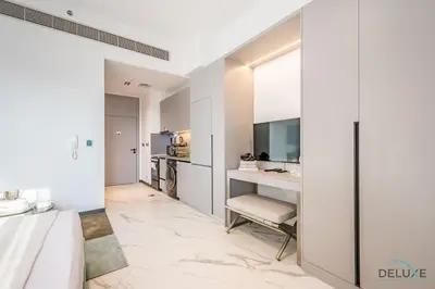a bedroom with white walls and a desk with a television at Appealing Studio in MAG EYE 890, Mohammad Bin Rashid City by Deluxe Holiday Homes in Dubai