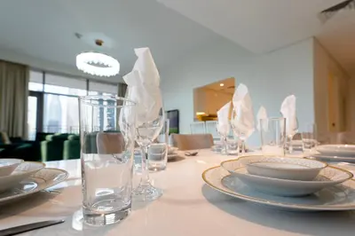 a white table with plates and glasses on it at Beautiful 2BR I Heart of BLVD I Downtown Dubai in Dubai