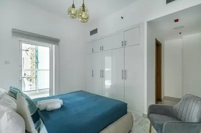 a bedroom with a blue bed and a chair at ShoresInn - Radiant 1BR in Dubai Marina in Dubai