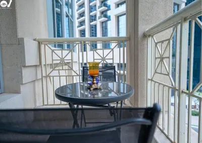 a glass table on a balcony with a drink on it at Luxury 2BR Suite I Garden View I Downtown Dubai in Dubai