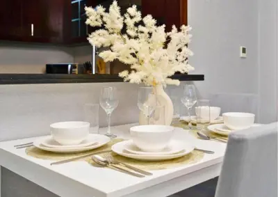 a white table with a vase of white flowers on it at Stylish 2BR I Partial Burj View I Downtown Dubai in Dubai