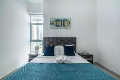 a bedroom with a large bed with blue pillows at ShoresInn - Tranquil 1BR in Dubai Marina in Dubai