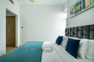 a bedroom with a large white bed with blue pillows at ShoresInn - Tranquil 1BR in Dubai Marina in Dubai
