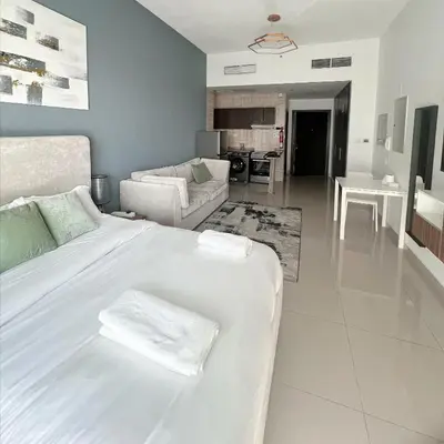 a white bedroom with a large white bed and a living room at Studio Apartment with Stunning Marina Views in Dubai