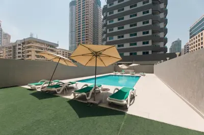 a pool with chairs and umbrellas on a rooftop at Studio Apartment with Stunning Marina Views in Dubai