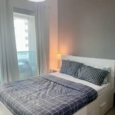 a bedroom with a bed with a blue comforter and a window at Studio with Sunset Views at Dubai Marina in Dubai