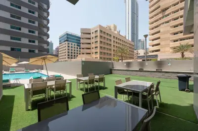 a rooftop patio with tables and chairs and a pool at Studio with Sunset Views at Dubai Marina in Dubai