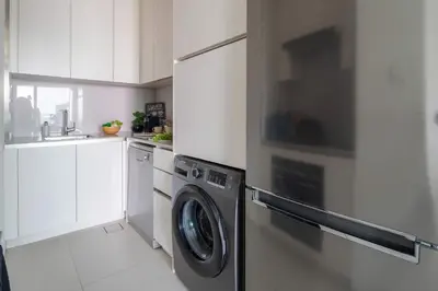a kitchen with a washing machine in a white kitchen at Frank Porter - The Address JBR in Dubai