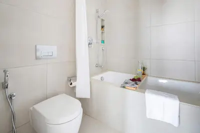 a white bathroom with a toilet and a bath tub at Frank Porter - The Address JBR in Dubai