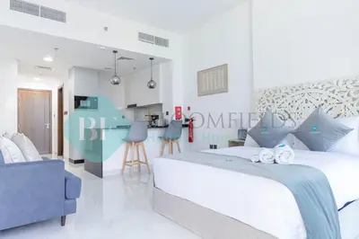 a bedroom with a large bed and a blue chair at Bloomfileds Cozy Stu In Unistate Supreme Residence in Dubai