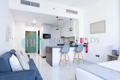 a living room with a blue couch and a kitchen at Bloomfileds Cozy Stu In Unistate Supreme Residence in Dubai