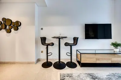 a living room with a table and two black stools at Cute studio in The Sterling by Omniyat in Dubai