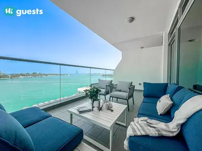 a living room with blue couches and a view of the ocean at HiGuests - Premier Beachfront Stylish 2BR Apt and Maid Room in Dubai