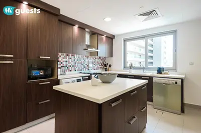 a kitchen with wooden cabinets and a counter top at HiGuests - Premier Beachfront Stylish 2BR Apt and Maid Room in Dubai