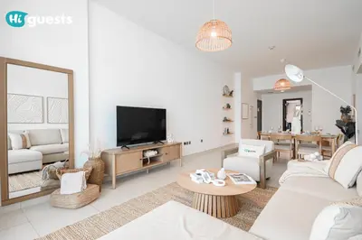 a living room with a couch and a tv at HiGuests - Premier Beachfront Stylish 2BR Apt and Maid Room in Dubai