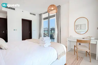 a white bedroom with a bed and a desk and a mirror at HiGuests - Premier Beachfront Stylish 2BR Apt and Maid Room in Dubai