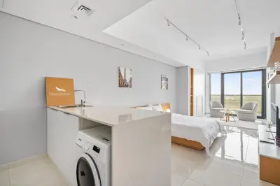 a white bedroom with a bed and a washing machine at Spacious Studio With Dubailand Charm in Dubai