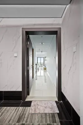 an open hallway with white marble walls and a doorway at Spacious Studio With Dubailand Charm in Dubai