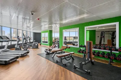 a gym with a green wall and tread machines at Spacious Studio With Dubailand Charm in Dubai