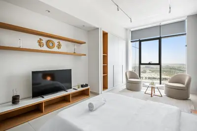 a white bedroom with a tv and a bed at Bright Studio In Vibrant Dubailand District in Dubai