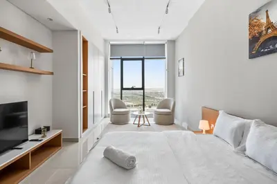 a bedroom with a large bed and a tv at Bright Studio In Vibrant Dubailand District in Dubai