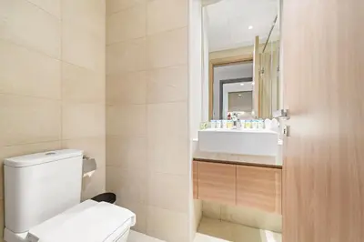a bathroom with a toilet and a sink and a mirror at Cozy 1BR with Pool View & Balcony in Dubai
