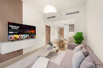 a living room with a couch and a tv on a wall at Cozy 1BR with Pool View & Balcony in Dubai