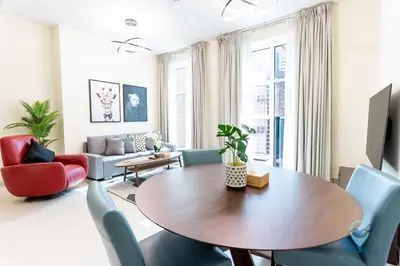 a living room with a wooden table and blue chairs at 2BR Stunning Luxury Heart of Marina Near Beach in Dubai