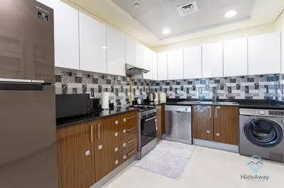 a kitchen with white cabinets and a washer and dryer at 2BR Stunning Luxury Heart of Marina Near Beach in Dubai
